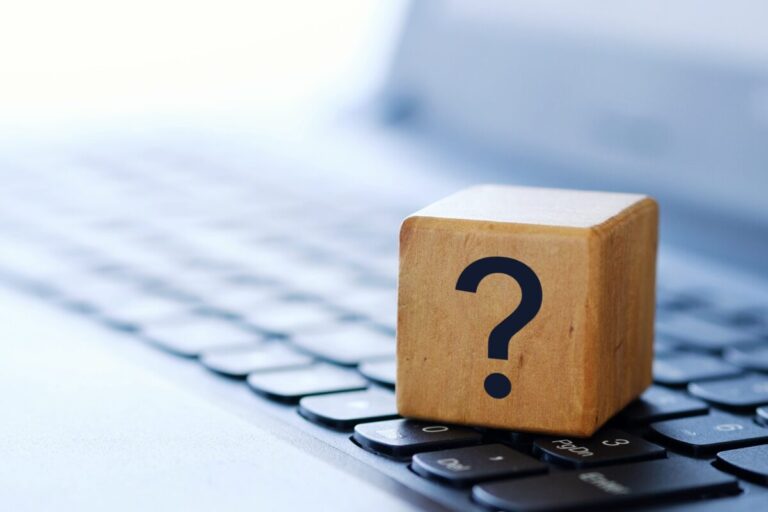 A question mark on a wooden cube on a computer keyboard